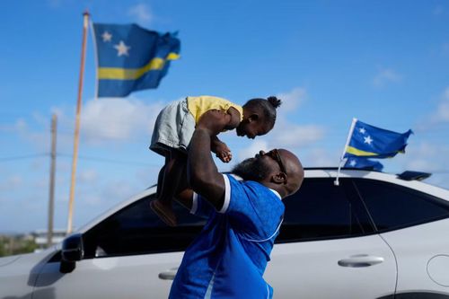 Brenton Balentien, thủ lĩnh nhóm cổ động viên đội tuyển Curaçao, nhấc bổng con gái tại Willemstad ngày 16/5/2026.