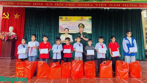 Cán bộ Đồn Biên phòng Nậm Nhừ trao học bổng tặng học sinh có hoàn cảnh khó khăn, nỗ lực vươn lên trong chương trình giao lưu văn nghệ “Thiếu nhi biên cương noi gương Bác Hồ”. Ảnh: Xuân Điềm