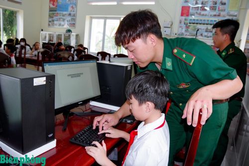 Cán bộ Đồn Biên phòng Vĩnh Hải hướng dẫn các em học sinh thực hành trên máy tính trong mô hình “Đồn Biên phòng Vĩnh Hải đồng hành cùng các em học sinh chuyển đổi số”. Ảnh: Văn Long