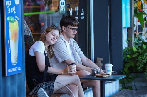 Hai bạn trẻ đến từ Nga thưởng thức cà phê tại một quán trên đường Bạch Đằng để chờ những màn pháo hoa rực rỡ đêm khai mạc. Ảnh: NGỌC PHÚ
