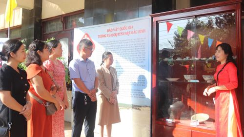 Khách tham quan nghe thuyết minh, giới thiệu về các cổ vật gốm sứ được trưng bày tại triển lãm xuân 2026