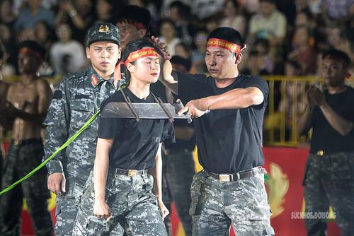 Trước giờ biểu diễn tại Hội thao Công an nhân dân năm 2026, nữ chiến sĩ được đồng đội hỗ trợ kiểm tra tư thế và điểm tiếp xúc giữa yết hầu với lưỡi đao.