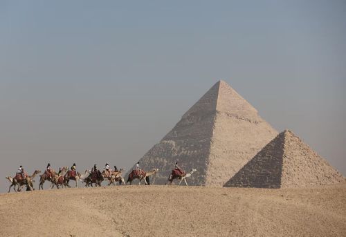  Du khách cưỡi lạc đà dọc cao nguyên trước đại kim tự tháp Giza, Ai Cập, năm 2022. Ảnh: Reuters.