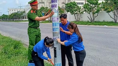 Công an và đoàn viên, thanh niên phường Bình Dương tham gia bóc xóa quảng cáo vặt sai quy định.