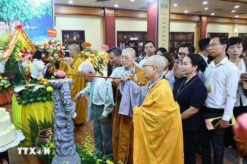 Các đại biểu và Phật tử thực hiện nghi thức tắm Phật. (Ảnh: Minh Đức/TTXVN)