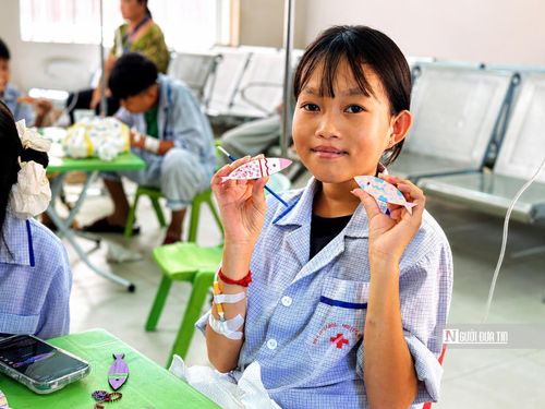 Thu Hằng cầm trên tay những chú cá gỗ do chính mình tô màu trong buổi sinh hoạt cùng các bệnh nhi.