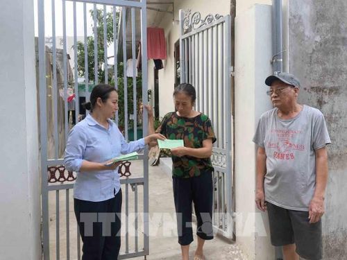 Cán bộ phường Ngô Quyền tặng thẻ xanh cho hộ gia đình phân loại rác đúng quy định. Ảnh: Hoàng Ngọc - TTXVN