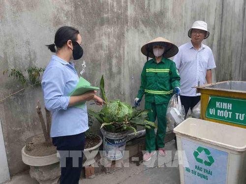 Cán bộ phường Ngô Quyền giám sát, nhắc nhở hộ dân phân loại rác sinh hoạt đúng quy định. Ảnh: Hoàng Ngọc - TTXVN