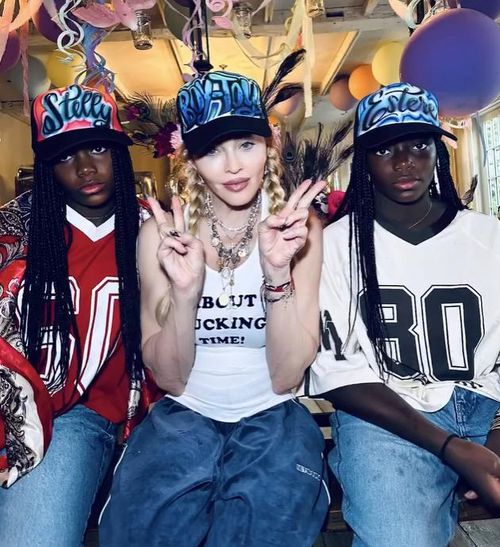 Madonna diện áo tank top gân màu trắng với dòng chữ “About f*ckin time!” được đính đá xanh nổi bật. Ảnh: IGNV