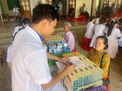 Nhân viên y tế cấp phát thuốc và hướng dẫn người dân chăm sóc sức khỏe.