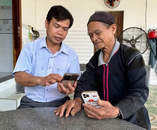  Trưởng ban Xây dựng Đảng xã Kim Sơn trao đổi với già làng Đinh Sinh về nhận diện các thông tin xấu, độc trên mạng xã hội. Ảnh: N.H 