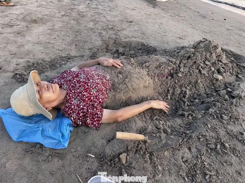 Bà Lê Thị Kề (80 tuổi) cho biết bà ra biển từ 4h30 mỗi ngày. Bị thoái hóa cột sống nhiều năm, bà tìm đến phương pháp chôn cát và cảm nhận sức khỏe cải thiện rõ rệt.