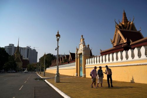  Du khách đi bộ cùng hướng dẫn viên bên ngoài Cung điện Hoàng gia ở Phnom Penh, Campuchia, năm 2020. Ảnh: Reuters. 