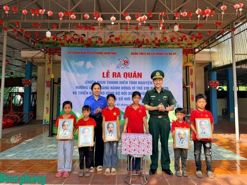 Cán bộ Đồn Biên phòng Nậm Nhừ trao tặng ảnh Bác Hồ, quà cho các cháu học sinh Trường Mầm non Nậm Nhừ. Ảnh: Mùa Tùng