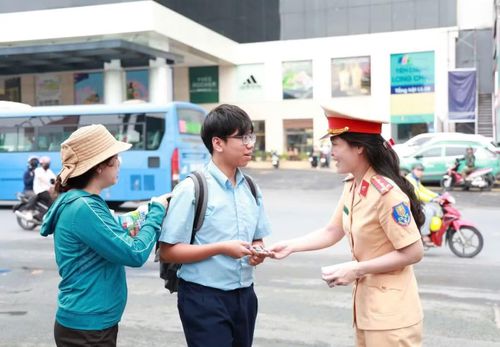 Nữ chiến sĩ thuộc Đội CSGT Rạch Chiếc (Phòng Cảnh sát giao thông, Công an TPHCM) tặng bút cho thí sinh trước giờ thi môn Tiếng Anh chiều 1/6 tại điểm thi THCS Lê Quý Đôn, phường Thủ Đức.