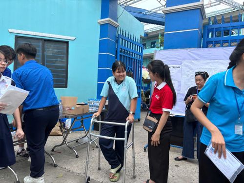 Đặc biệt, tại điểm thi Trường THCS Lê Lợi có hai thí sinh phải chống nạng đến phòng thi. Hình ảnh các em được tình nguyện viên và người thân hỗ trợ di chuyển khiến nhiều phụ huynh xúc động. Dù gặp khó khăn trong việc đi lại nhưng cả hai vẫn giữ tinh thần khá thoải mái trước giờ làm bài. (Ảnh) Thí sinh bị bệnh cơ xương được hỗ trợ di chuyển dự thi. (Ảnh: Mỹ Hậu)