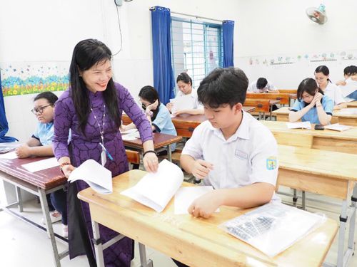 Cán bộ coi thi phát giấy thi cho thí sinh. Ảnh: THU TÂM.