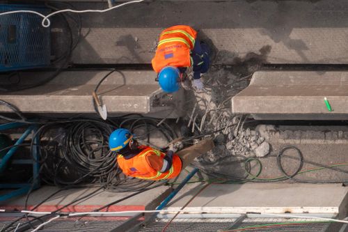 Bên trong khu vực rào chắn, hàng chục công nhân cùng máy móc chuyên dụng đang tập trung sửa chữa các hạng mục mặt cầu. Một số vị trí đã được bóc lớp bê tông nhựa cũ để xử lý nền mặt đường và thay thế các bộ phận khe co giãn xuống cấp sau nhiều năm khai thác.
