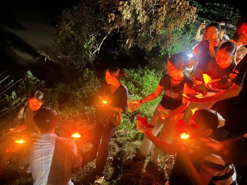 Người dân truyền tay nhau những ngọn nến hoa đăng thả xuống sông.