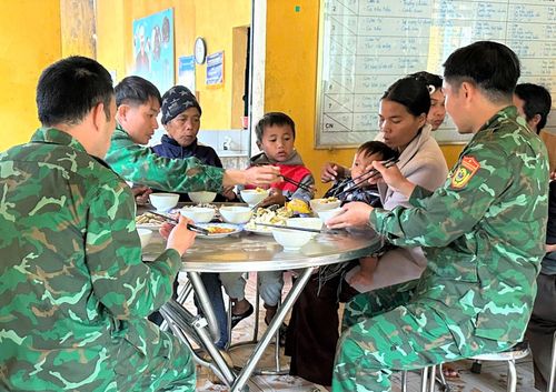 Cán bộ, chiến sĩ biên phòng chăm lo bữa ăn cho người dân biên giới. Ảnh: SONG NGUYÊN