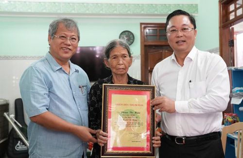 Chủ tịch Ủy ban MTTQ Việt Nam thành phố Lê Trí Thanh (bìa phải) trao thiệp mừng thọ 90 tuổi cho cụ Phạm Thị Hiệu (xã Núi Thành). Ảnh: HỒ QUÂN