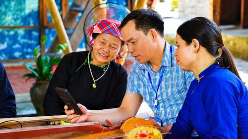 Thành viên tổ cấp giấy chứng nhận quyền sử dụng đất lưu động hướng dẫn người dân sử dụng điện thoại thông minh để tra cứu, theo dõi tiến độ giải quyết hồ sơ.