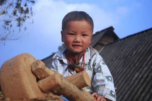 Em bé vùng cao bên chiếc xe gỗ. Ảnh: Huy Trường
