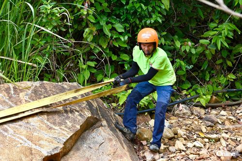 Một lái phụ đang móc dây tời xe với tảng đá để hỗ trợ xe vượt địa hình.
