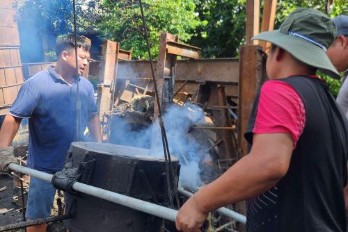 Những người thợ làng Trà Đông phối hợp thực hiện công đoạn rót đồng nóng chảy vào khuôn đúc trống đồng và thần công