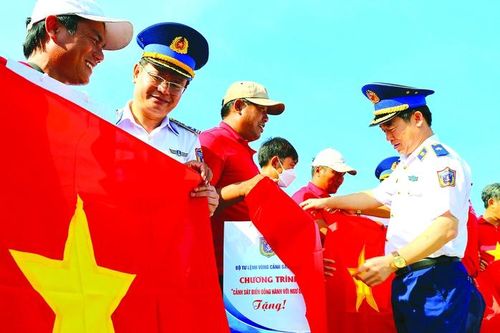 Thiếu tướng Bùi Quốc Oai, Chính ủy Cảnh sát biển Việt Nam (phải, hiện là Trung tướng), trao cờ Tổ quốc cho ngư dân Lý Sơn, tỉnh Quảng Ngãi vào ngày 28-5-2022