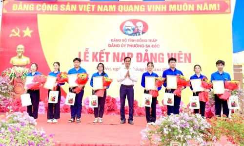 Đồng chí Nguyễn Văn Vũ Minh, Tỉnh ủy viên, Bí thư Đảng ủy phường Sa Đéc trao Quyết định và tặng hoa chúc mừng các học sinh ưu tú được kết nạp vào Đảng. Ảnh: NGỌC DUY