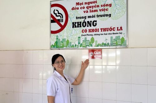 Nhân viên y tế bên bảng cấm hút thuốc lá tại Trung tâm Y tế khu vực Lâm Hà