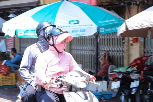 Nhiệt độ ngoài trời tăng cao, có lúc trên 50 độ C, khiến người dân di chuyển ngoài đường phải trang bị kín mít với áo chống nắng, khẩu trang, găng tay, mũ rộng vành. Ảnh: Hoàng Hiếu - TTXVN