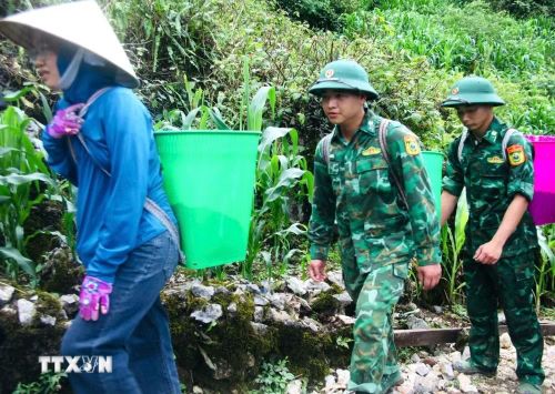 Cán bộ, chiến sỹ Đồn Biên phòng Tùng Vài cùng nhân dân địa phương vận chuyển vật liệu phục vụ thi công đường bê tông tại thôn Chín Sang, xã Tùng Vài (Tuyên Quang). (Ảnh: Hoàng Chính/TTXVN phát)