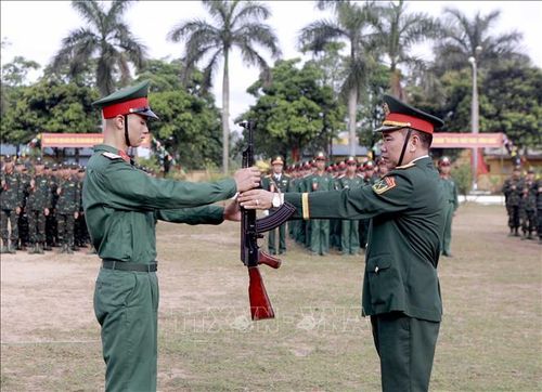 Trung tá Nguyễn Văn Lượng, Trung đoàn trưởng Trung đoàn Bộ binh 24, thực hiện nghi thức trao súng cho chiến sĩ mới tại Lễ tuyên thệ chiến sĩ mới năm 2026. Ảnh: Hoàng Hùng/TTXVN