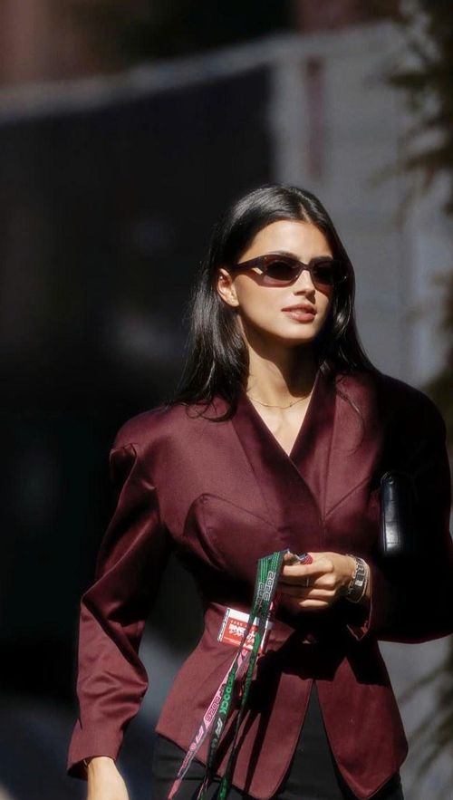 Francisca Gomes, bạn gái Pierre Gasly, sải bước tại đến trường đua với bộ suit tông đỏ rượu vang. Chất liệu bộ trang phục của cô có độ bóng nhẹ, giúp tổng thể nổi bật dưới ánh nắng, trong khi phần chiết eo và cổ chữ V tạo hiệu ứng tôn dáng rõ rệt. Cô hoàn thiện vẻ ngoài với mái tóc dài duỗi thẳng rẽ ngôi giữa. Cặp đôi công khai hẹn hò từ tháng 1/2023, hiện Francisca hoạt động nổi bật trong lĩnh vực người mẫu. Ảnh: @kikagomes/IG.