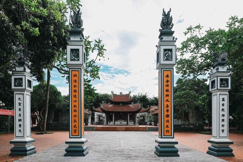 Trục thần đạo dẫn vào đình Phúc Xá, hai bên là hệ thống trụ biểu và câu đối, phía sau là mái đình cổ, nơi thờ Thái úy Việt Quốc công Lý Thường Kiệt, danh tướng Đào Kỳ, Phương Dung công chúa và các vị thành hoàng được người dân tôn kính. Ảnh: Phạm Tuấn Anh - TTXVN