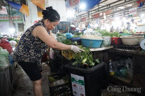 Tiểu thương Nguyễn Thị Liên phân loại rác tại quầy, gom các loại rau, vỏ dứa, gốc rau...vào thùng rác hữu cơ