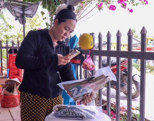 Chị Ngô Yến Linh (ấp Cái Nước Biển, xã Phú Tân), chụp ảnh sản phẩm cá khô để đăng tải trên mạng xã hội, quảng bá và giới thiệu sản phẩm đến khách hàng.