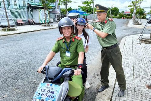 Cán bộ công an Cà Mau hỗ trợ em Ngô Diễm My đến điểm thi Trường trung học phổ thông Nguyễn Việt Khái đúng giờ, an toàn.