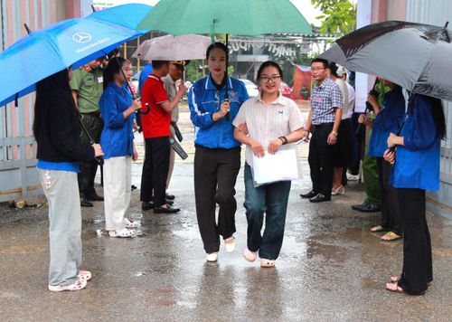  Đoàn viên, thanh niên cầm ô dù che mưa đưa đón thí sinh vào điểm thi 