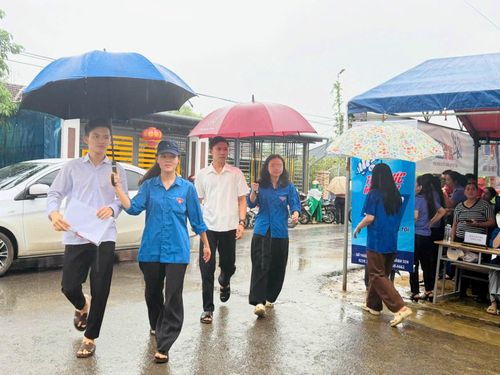  Đoàn viên, thanh niên cầm ô dù che mưa đưa đón thí sinh vào điểm thi 