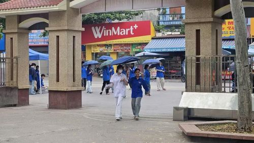 Thí sinh được tình nguyện viên hỗ trợ che mưa tại Điểm thi.