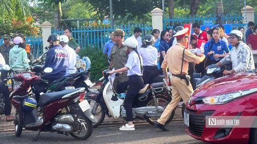 Cán bộ CSGT phối hợp cùng lực lượng thanh niên tình nguyện bảo đảm trật tự, an toàn giao thông tại khu vực cổng điểm thi trong ngày đầu diễn ra Kỳ thi tốt nghiệp THPT năm 2026.