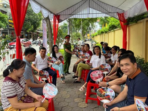 Phụ huynh vui vẻ nhận chiếc quạt "đa chức năng" rất hữu ích. Ảnh: T.L