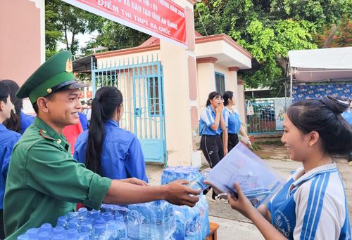 Chiến sĩ đồn Biên phòng Lạc Quới trao nước uống cho học sinh Trường THPT Ba Chúc (xã Ba Chúc).