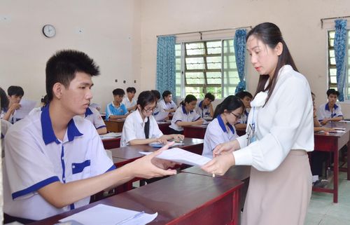 Cán bộ coi thi tại điểm thi Trường THPT Hòn Đất, xã Hòn Đất, phát phiếu trả lời trắc nghiệm cho thí sinh. Ảnh: MI NI