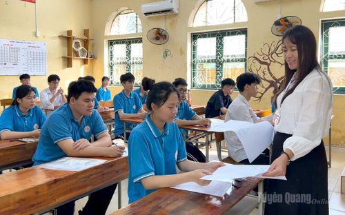 Cán bộ coi thi tại điểm thi trường THPT Ỷ La phát giấy thi và hướng dẫn thí sinh điền thông tin cá nhân. Ảnh: Thúy Nga