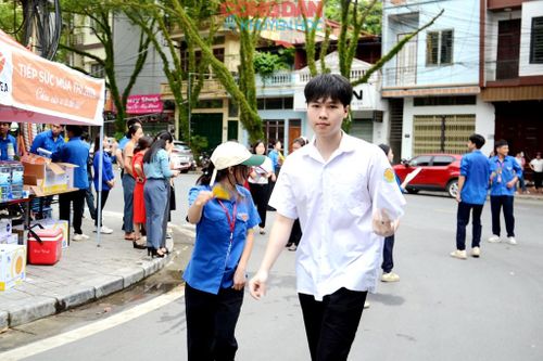 Một thí sinh được đoàn viên thanh niên phường Cam Đường hướng dẫn đến làm thủ tục vào phòng thi. Ảnh: Quốc Hồng