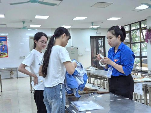 Đoàn viên, thanh niên xã Đông Anh, hỗ trợ thí sinh bảo quản đồ dùng cá nhân trước khi vào phòng thi. Ảnh:MK